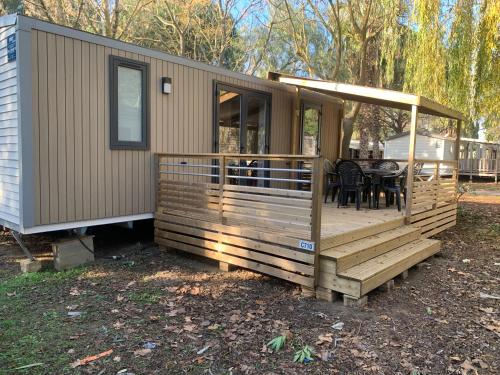 uma casa móvel com um deque com uma mesa e cadeiras em Camping 4 étoiles Le Bosc Saint Cyrpien Mobil Home em Saint-Cyprien