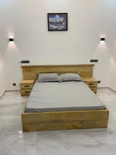 ein Schlafzimmer mit einem Holzbett in einem weißen Zimmer in der Unterkunft Appartement Kekely in Lomé