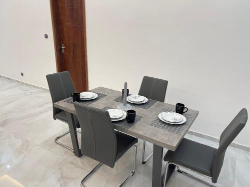 a wooden table with chairs and plates on it at Appartement Kekely in Lomé