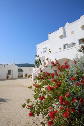 a white building with red flowers in front of it at Masseria Parco della Grava in Pezze di Greco