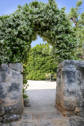 an archway with a table and chairs in a garden at Masseria Parco della Grava in Pezze di Greco