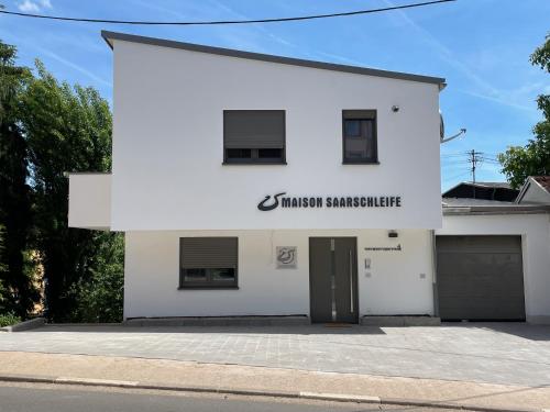 a white building with a sign that reads trinity supermarket at Maison Saarschleife Mettlach in Mettlach