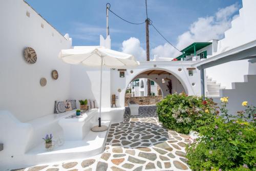a white courtyard with an umbrella and some plants at Keti Kapri in Plaka