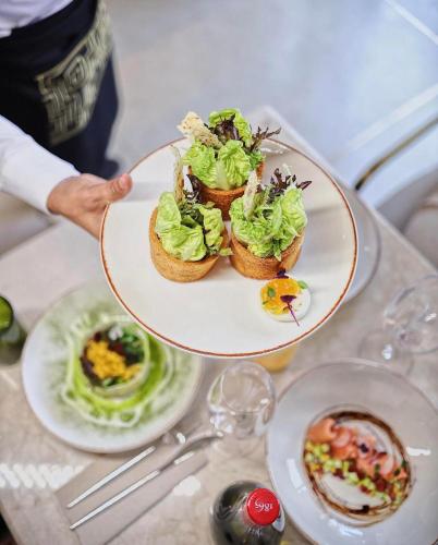 a person holding a plate of food on a table at Shepherd Hotel in Amman