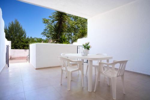 una sala da pranzo bianca con tavolo e sedie bianchi di Case bianche del Capitolo a Monopoli