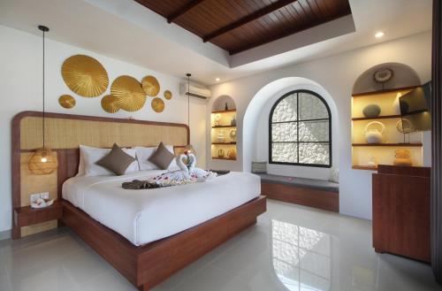 a bedroom with a large white bed and a window at Sudha Villa Bali Anyelir in Seminyak