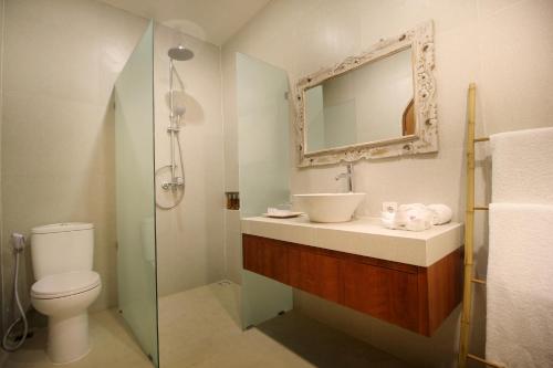 a bathroom with a sink and a toilet and a mirror at Sudha Villa Bali Anyelir in Seminyak