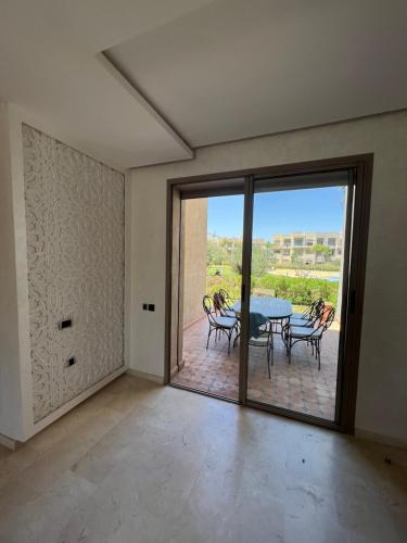 Habitación con mesa, sillas y puerta de cristal. en Prestigia 3 chambres piscine, en Marrakech