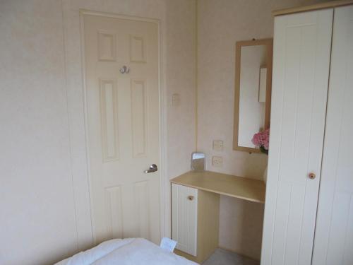 a bedroom with a door and a sink and a mirror at Coral Beach : The Richmond:- 6 Berth, Blow heated in Ingoldmells