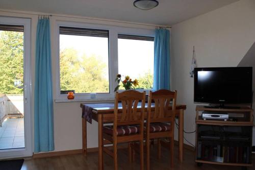a dining room with a table and a television and two windows at Müritzbrise in Sietow