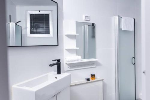 bagno bianco con lavandino e specchio di O&O Group - The SeaGate Estate suites - Suite 3 a Rishon LeẔiyyon