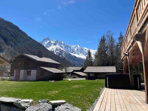 a building with mountains in the background with a grass field at Chalet Le petit paradis - Chamonix-Mont-Blanc in Chamonix-Mont-Blanc