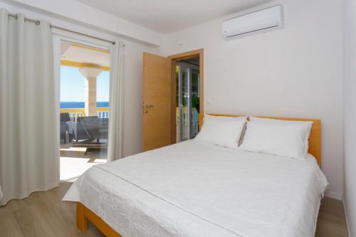 a bedroom with a white bed and a view of the ocean at Apartments Beach Side Brela in Brela