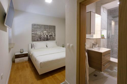 Apartments Beach Side Brela في بريلا: غرفة نوم بسرير ومغسلة ومرآة