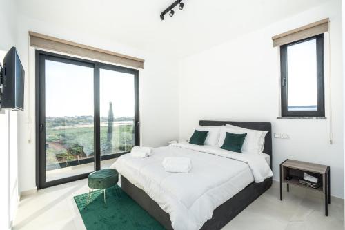 a white bedroom with a large bed and large windows at Tsiolakki Homes Luxury Villas in Protaras