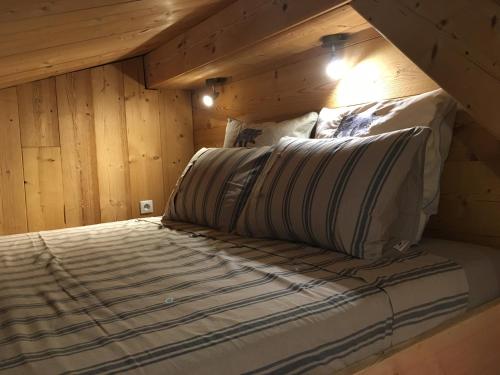 a bed in a room with wooden walls and ceilings at LES BALCONS DU PHENY LE REFUGE in Gérardmer
