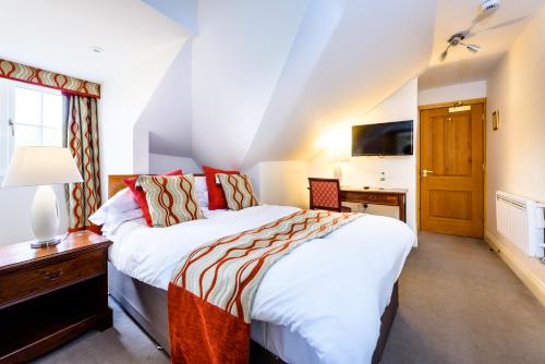 a bedroom with two beds and a desk and a television at Rectory Farm in Cambridge