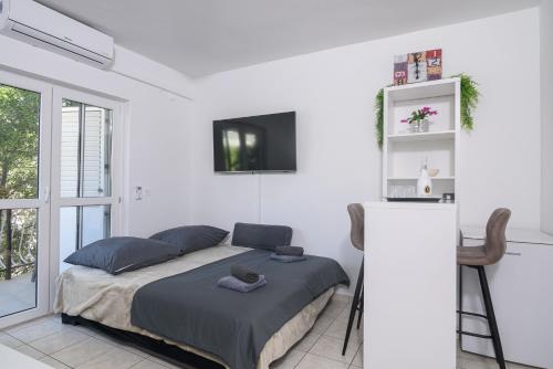 a white bedroom with a bed and a tv at L&L in Okrug Gornji
