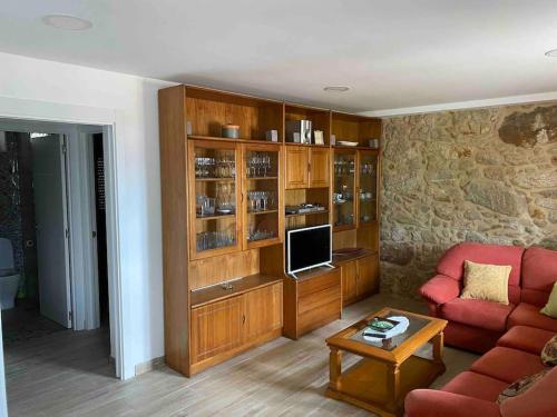 sala de estar con sofá rojo y TV en J. Casa con vistas en Lira - Carnota, en Lira