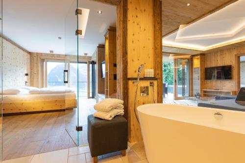 a bathroom with a tub and a bedroom with a bed at Chalet Residenz Zillertal Mühlermoos in Ramsau im Zillertal