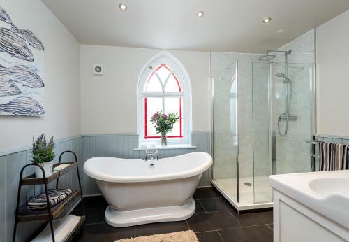 a bathroom with a tub and a shower and a sink at CHESTER'S ONLY TIN CHAPEL - UNIQUE, SPACIOUS 2 BEDROOMS, GARDEN AND FREE PARKING in Chester