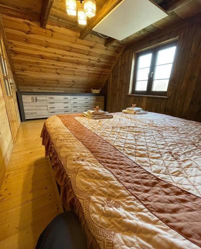 a large bed in a room with wooden walls at Domek u Janiego in Milówka