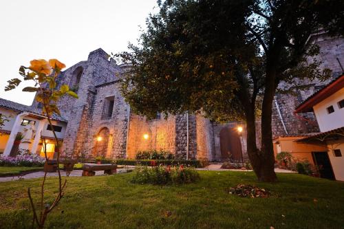 a large stone building with a tree in a yard at Hotel Monasterio San Pedro in Cusco