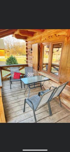 a patio with a table and chairs on a wooden deck at Domek u Janiego in Milówka