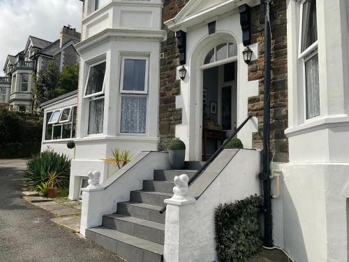 a white house with stairs leading to the door at Cairn House in Ilfracombe