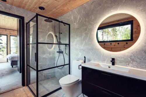 a bathroom with a shower and a toilet and a sink at Saunamäki Resort - Lux Villa in Salo