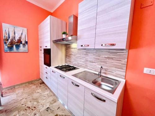 a kitchen with a sink and an orange wall at Domus Aurea in Isola delle Femmine
