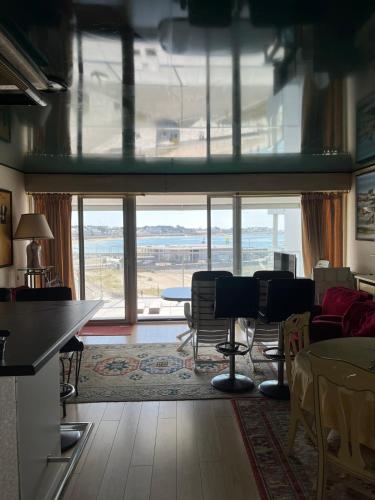 - un salon avec une table, des chaises et une grande fenêtre dans l'établissement Appartement port maria vue mer, à Quiberon