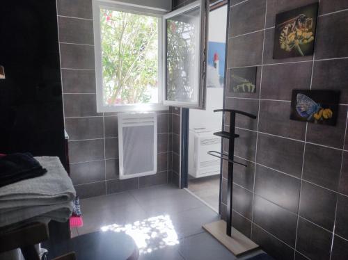 uma casa de banho com uma janela e uma parede em azulejo em Chambre et salle d'eau dans dépendance 20 m2, vélos em Les Sables-dʼOlonne