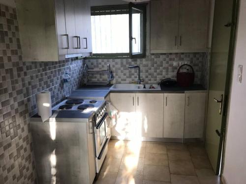 a kitchen with white cabinets and a stove top oven at Katakolo Stone-paved Family Heaven in Katakolo