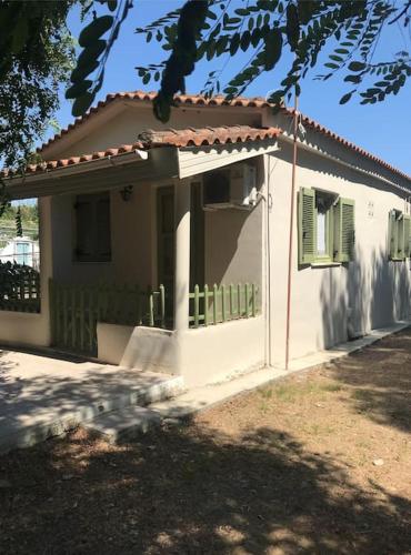 a small white house with a porch and a window at Katakolo Stone-paved Family Heaven in Katakolon