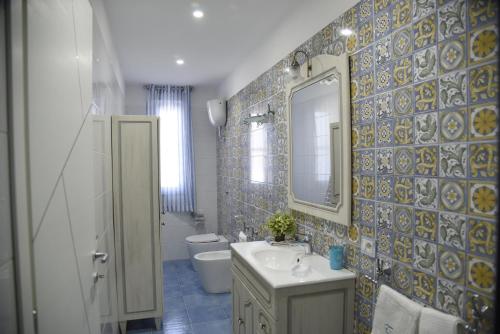a bathroom with a sink and a toilet and a mirror at La Laura di Paestum - case vacanze in Capaccio-Paestum