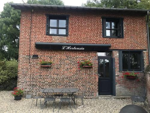 a brick building with a table in front of it at L'Hortensia in Beuvron-en-Auge