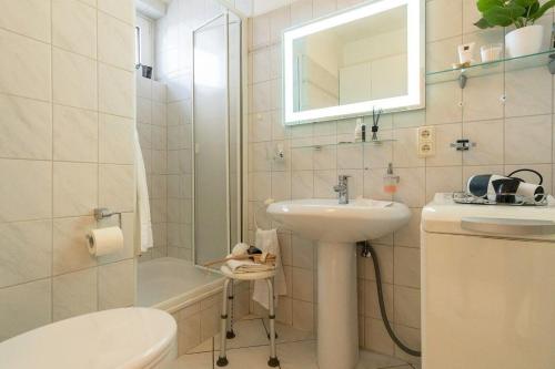een badkamer met een wastafel, een toilet en een spiegel bij Haus-des-Kurgastes-Wohnung-4 in Heiligenhafen
