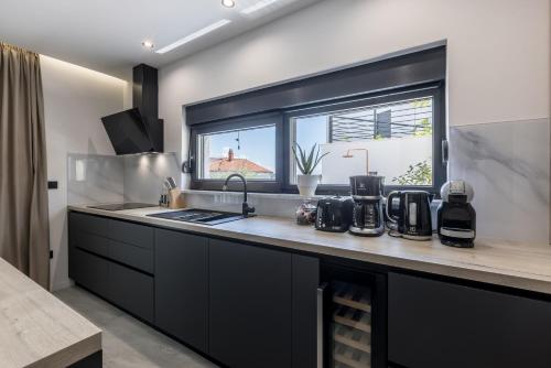 a kitchen with black cabinets and a window at Villa ToDo with heated pool and jacuzzi in Vinišće