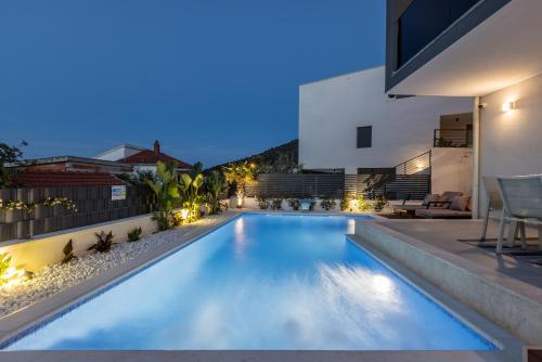 a swimming pool in the backyard of a house at night at Villa ToDo with heated pool and jacuzzi in Vinišće