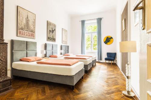 three beds in a room with wooden floors at Das Hostel in Krakow