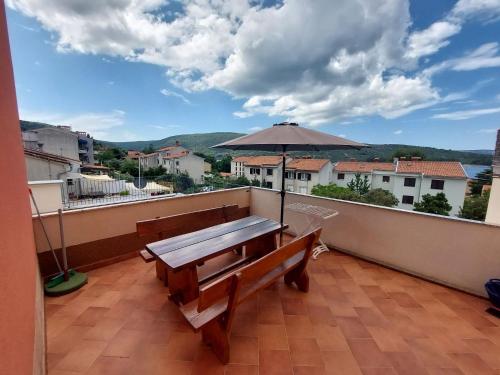 a balcony with a wooden bench and an umbrella at Apartment Adriatic, Cres in Cres