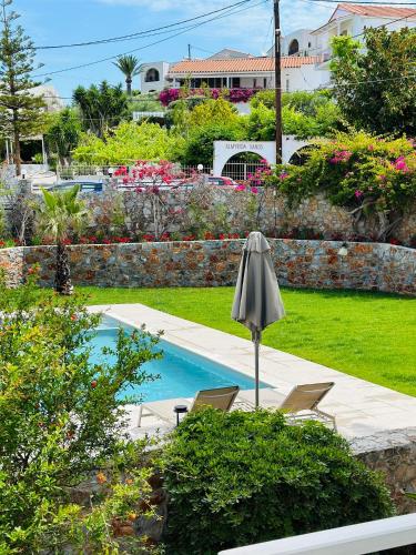a swimming pool with two chairs and an umbrella at Cost Mari Almyrida New by ZAGO Boutiqe hotels in Almirida