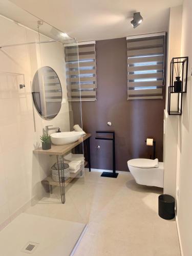 a bathroom with a sink and a toilet and a mirror at Apartment Vithea in Crikvenica