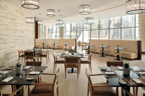 ein Restaurant mit Tischen und Stühlen und großen Fenstern in der Unterkunft Le Méridien City Center Doha in Doha