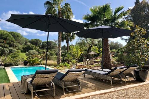 eine Gruppe von Stühlen und Sonnenschirmen neben einem Pool in der Unterkunft Casa Sereno in Benagil
