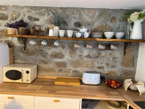 a kitchen with a microwave and a stone wall at Emily's House in Castro Daire