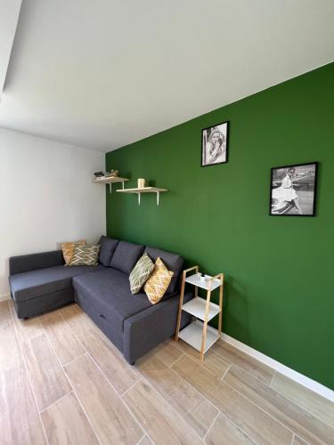 a living room with a couch and a green wall at Contemporary Haven in Châtenay-Malabry