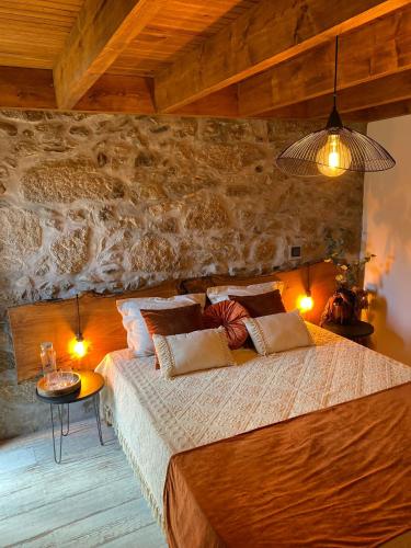 a bedroom with a large bed with a stone wall at Emily's House in Castro Daire