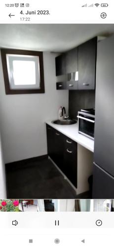 eine Küche mit schwarzen und weißen Schränken und einer Mikrowelle in der Unterkunft Lenilenii Bungalow in Jajce